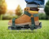 Aerator sprężynowy Master Garden RSAN zamocowany na bucie podczas dociskania kolców do darni trawnika