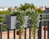 Antracytowa donica Urbi Case z efektem betonu zawieszona na balustradzie balkonu