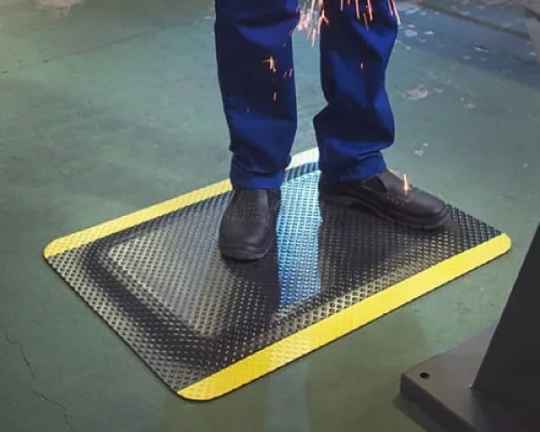 Zbliżenie na fakturę maty antyzmęczeniowej Komfort Safety podczas codziennej pracy w zakładzie produkcyjnym.