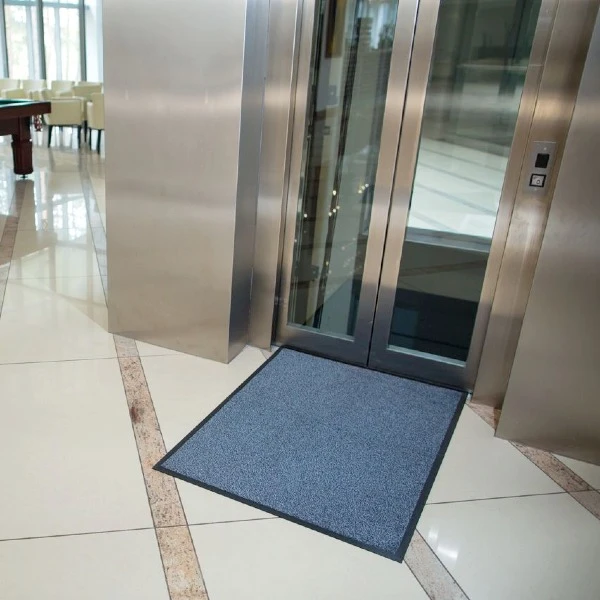 Mata pod drzwi z serii Strongmata w odcieniu stalowym dopasowana do przestrzeni przed windą hotelową.