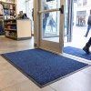 Granatowa wycieraczka pod drzwi Strongmata położona w strefie wejściowej sklepu.