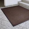Chłonna wycieraczka tekstylna Strongmata 85 x 120 cm w kolorze ciemnego brązu leżąca płasko w korytarzu biurowym przed schodami.