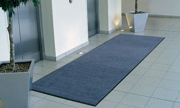 Długa wycieraczka osuszająca Strongmata 150x360 cm przylegająca płasko do podłogi przed strefa wind w biurowcu.
