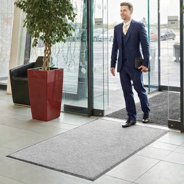 Elegancka szara wycieraczka tekstylna Monokolor położona przy wejściu do biurowca.