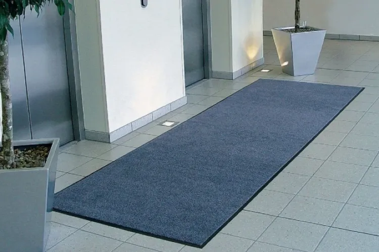 Długa wycieraczka osuszająca Strongmata 150x360 cm przylegająca płasko do podłogi przed strefa wind w biurowcu.