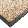 Zbliżenie na gumowe obrzeże oraz gęste nylonowe runo beżowego chodnika antypoślizgowego Monokolor 85x300 cm.
